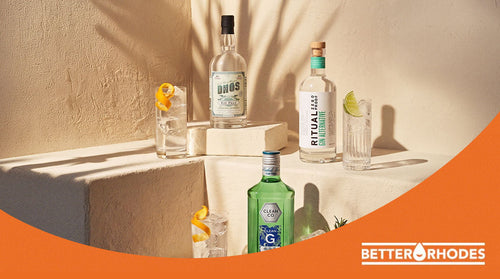 Three non-alcoholic gin bottles — DHOS, Ritual Zero Proof, and Clean Co — styled with ice-filled glasses on a sunlit tiered display