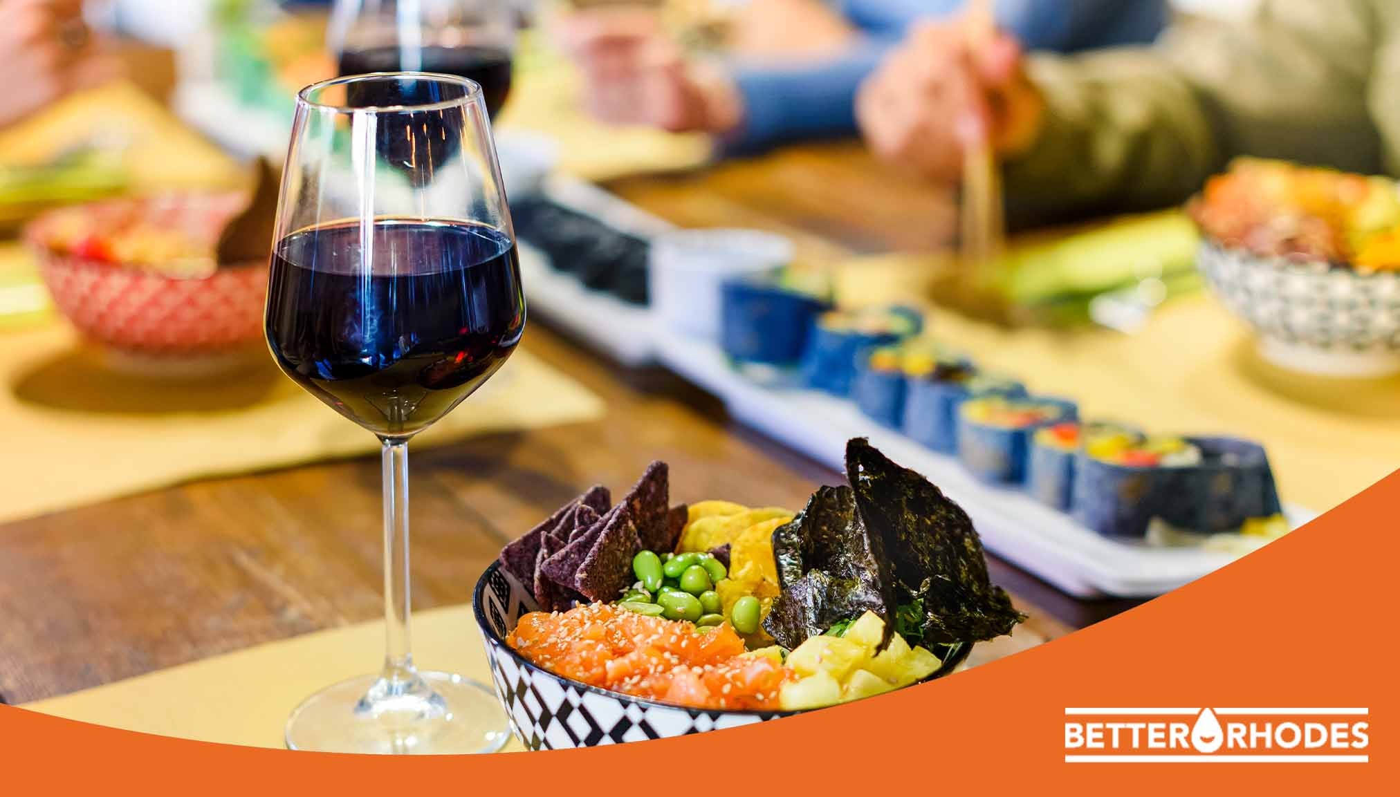 Glass of red alcohol-free wine paired with sushi and snacks on a dining table