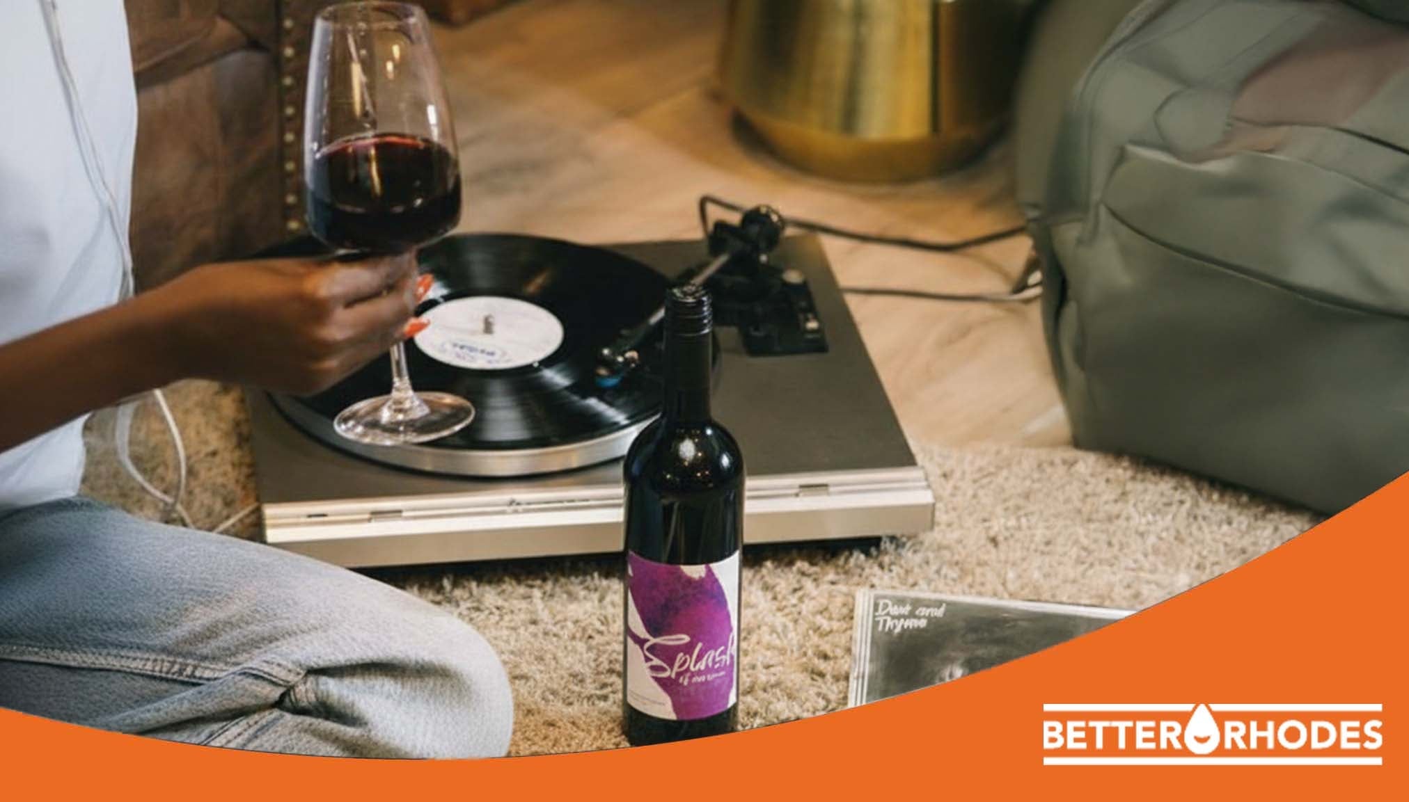 Person enjoying non-alcoholic red wine while listening to vinyl at home