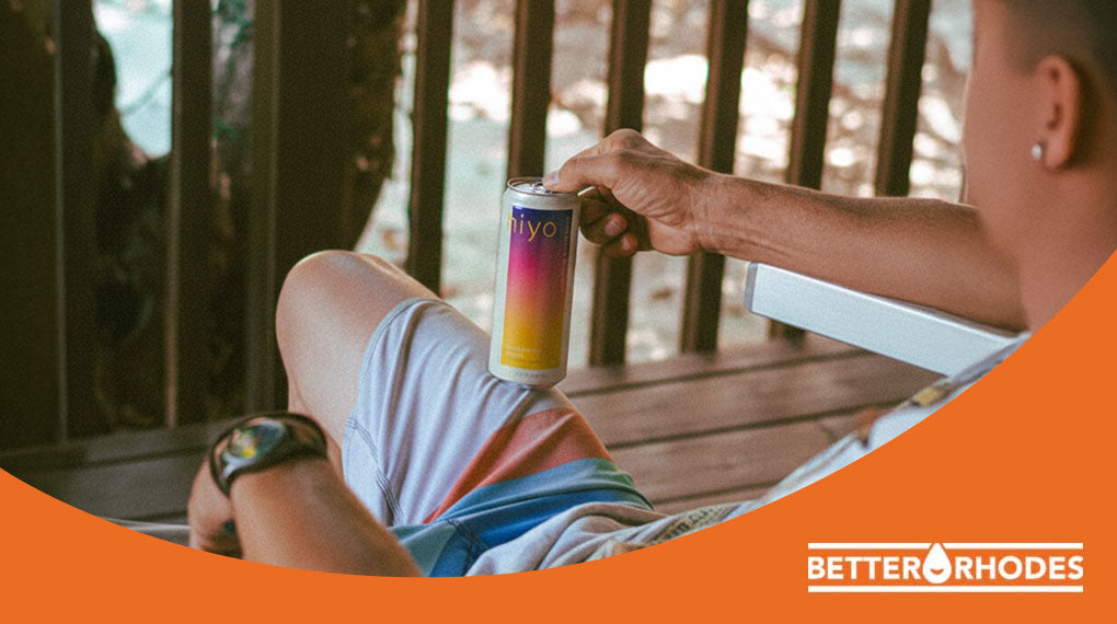 Person relaxing outdoors on a deck chair holding a Hiyo non-alcoholic functional beverage can