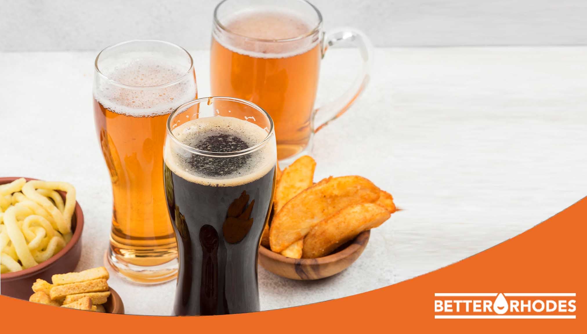 Glasses of non-alcoholic beer including lager and dark stout with snacks on a table