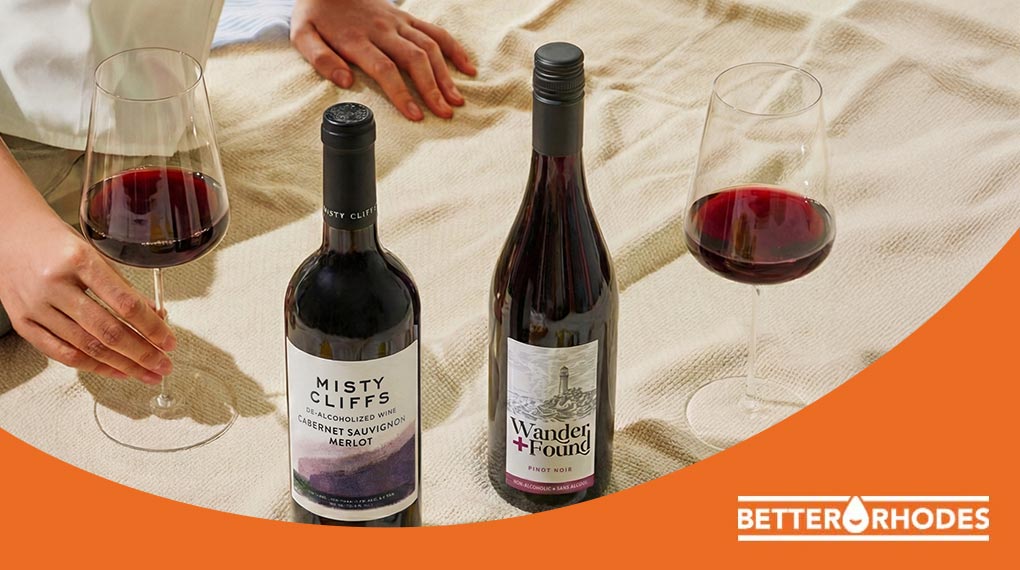 Non-alcoholic red wine bottles and glasses on a picnic blanket